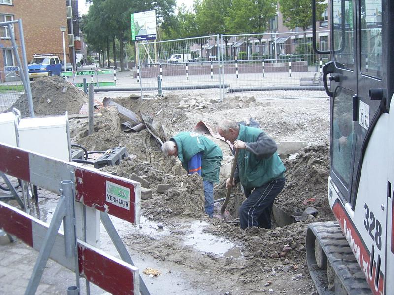 22-09-2004 de grondwerkers zijn bezig om de bekabeling en de leidingen vrij te maken om het riool aan te sluiten .