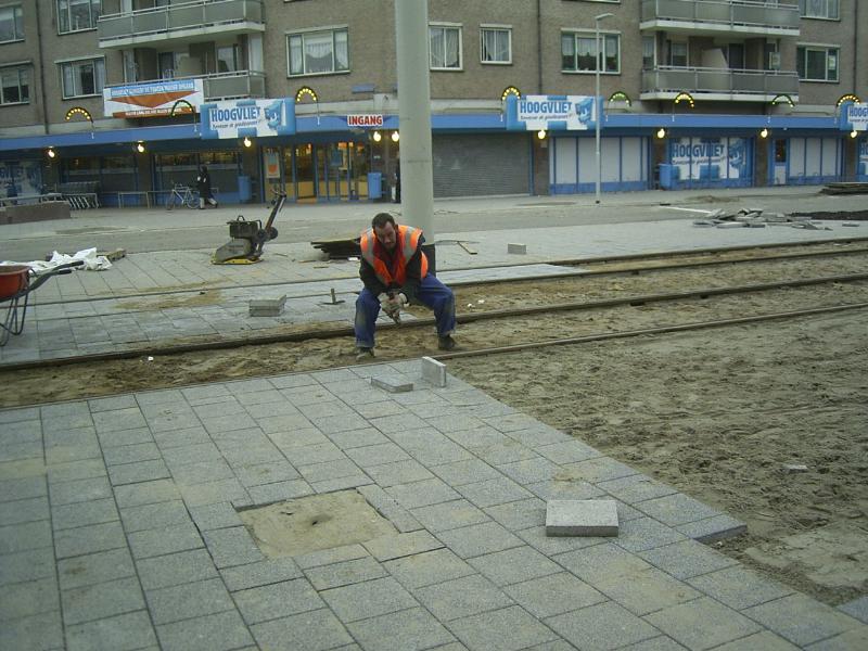01-12-2004 de straatmaker is hier bezig aan het bestraten bij de tramhalte.
