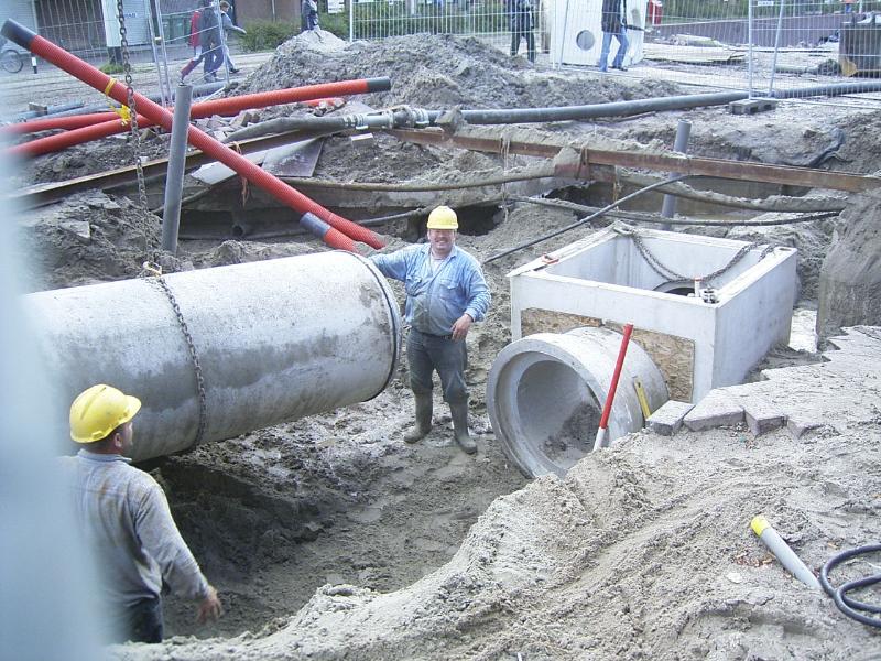 24-09-2004 de grondwerkers zijn bezig om een riool pijp aan te sluiten op de kolk .