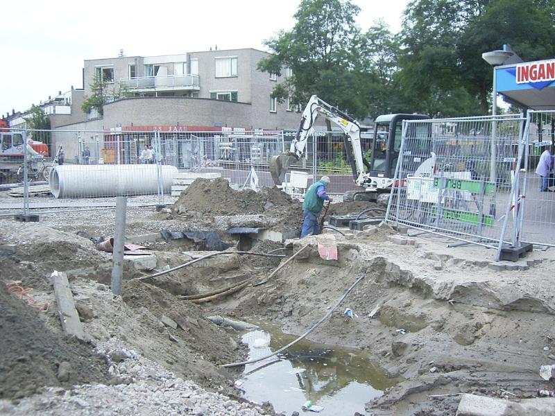 22-09-2004 grondwerkers zijn bezig om de kabels en de leidingen vrij te maken om het riool aan te kunnen sluiten.