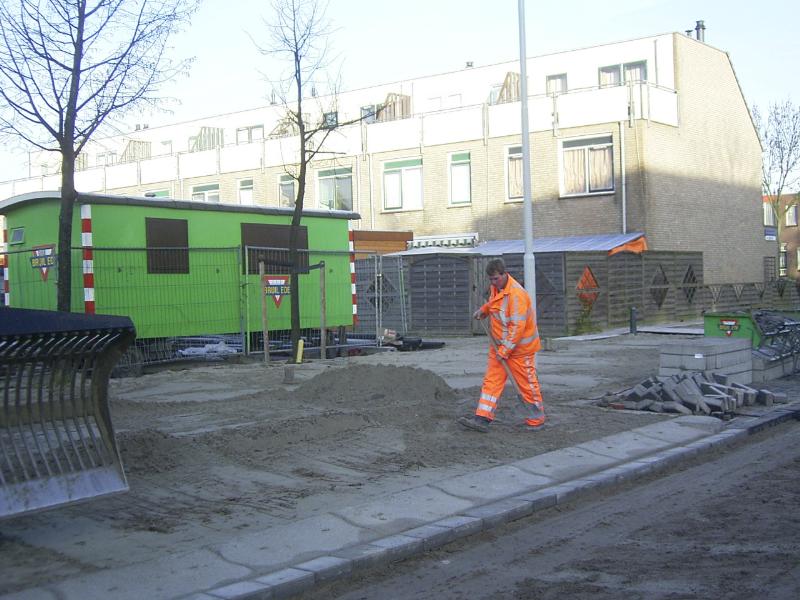 24-11-2004 de grondwerker is hier het zand glad aan het maken zodat de straatmakers de stoep kunnen bestraten.